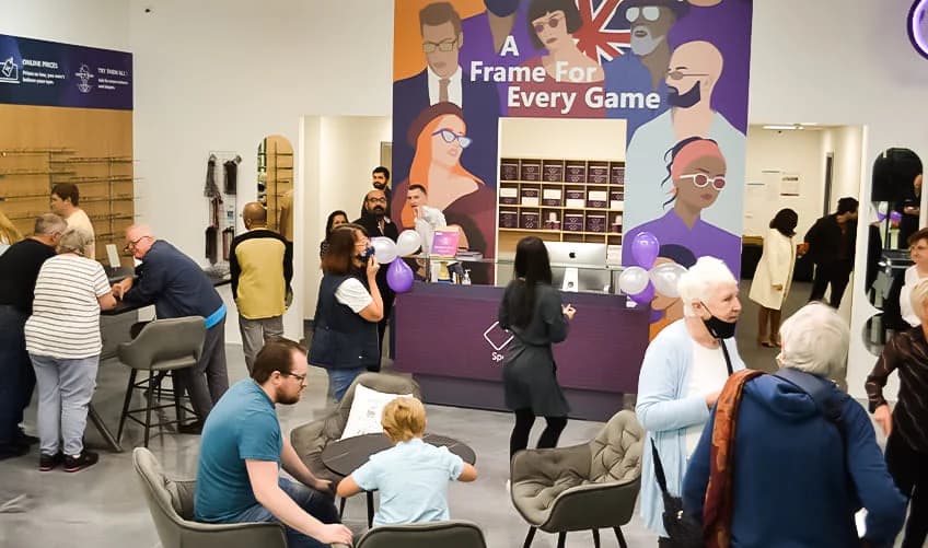Wide-angle view of Specscart Walkden store, featuring a modern glass facade, glowing purple logo, and inviting bright interior.