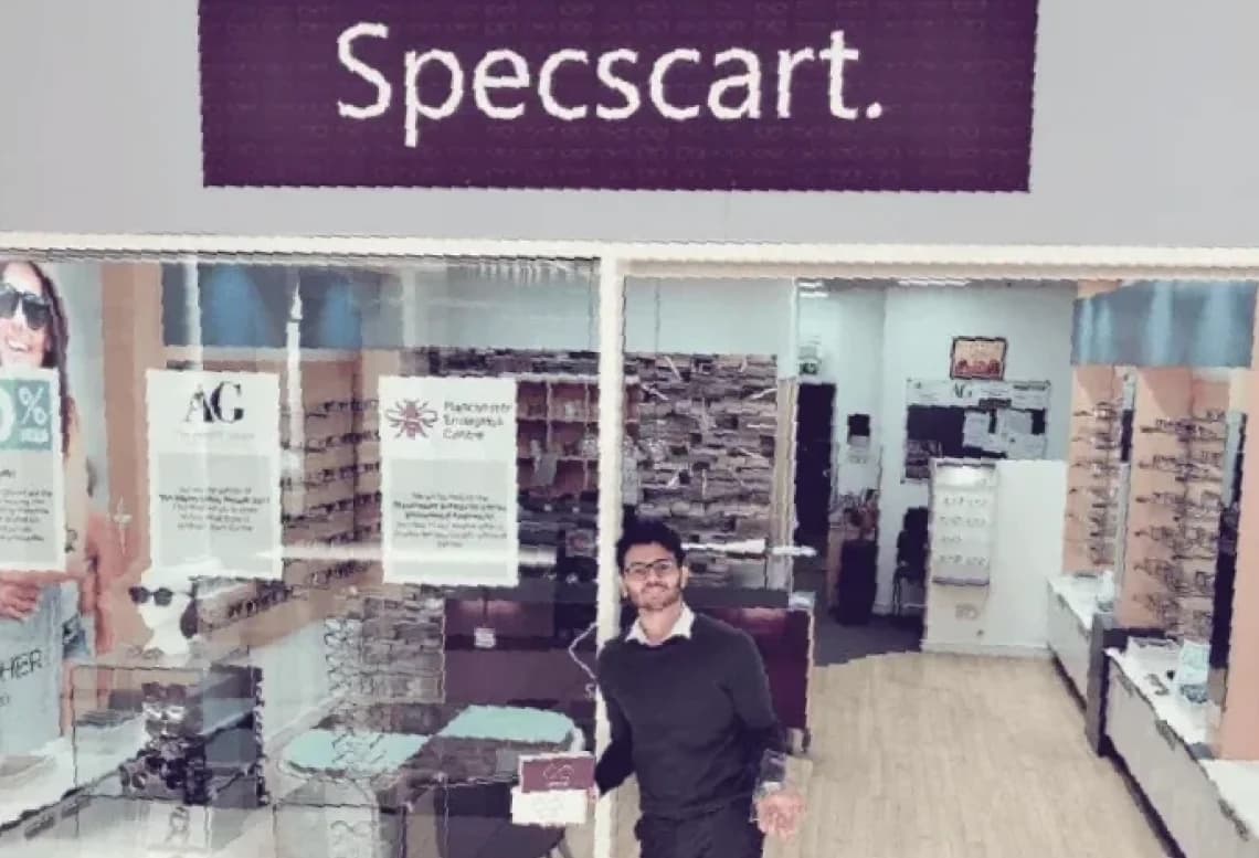 Front view of Specscart’s first store, with large signage and glass windows displaying promotional posters and eyewear displays. Sid Sethi, Specscart’s founder, stands at the entrance, marking the brand’s milestone following the Albert Gubay Award win in 2017.