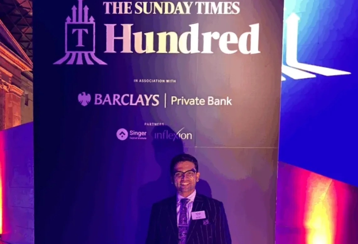 Specscart Founder Sid Sethi standing in front of a large event backdrop for The Sunday Times Hundred, featuring the logos of Barclays Private Bank and other partners. The image celebrates Specscart's recognition in The Sunday Times Seven Hottest Start-ups to Watch for companies led by founders under 35.
