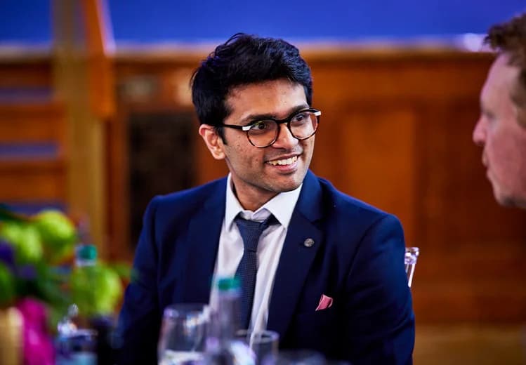 Sid Sethi, Specscart’s founder, seated at a table with event decor and drinks, wearing a navy blue suit and tie at the Venture Further Awards 2023.