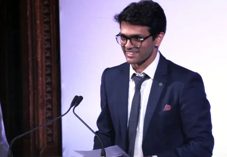 Sid Sethi, Specscart’s founder, wearing a suit and tie, speaking at a podium during The Venture Further Awards 2023, where he served as a member of the judging panel. Ornate wood panelling and event stage lighting set the professional scene.