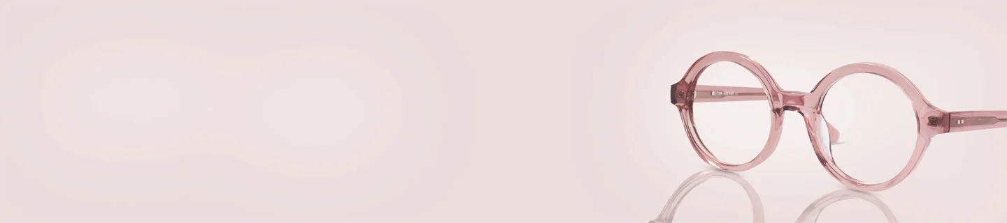 Pink Glasses Translucent crystal pink round glasses frames resting on a reflective soft pink background, showcasing a trendy and chic monochrome aesthetic.