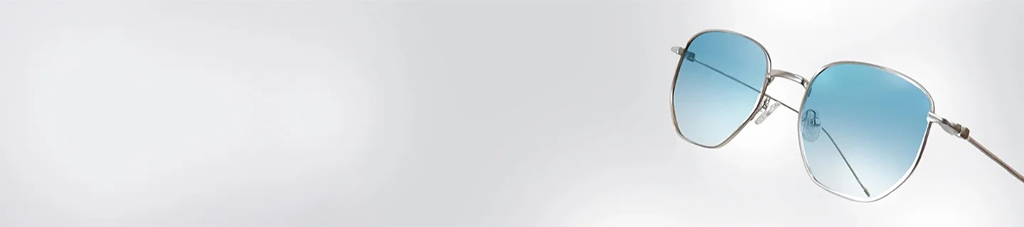 Silver Sunglasses A pair of lightweight silver sunglasses with blue-tinted lenses, displayed at an angle to highlight the sleek metal frame and minimalist design.