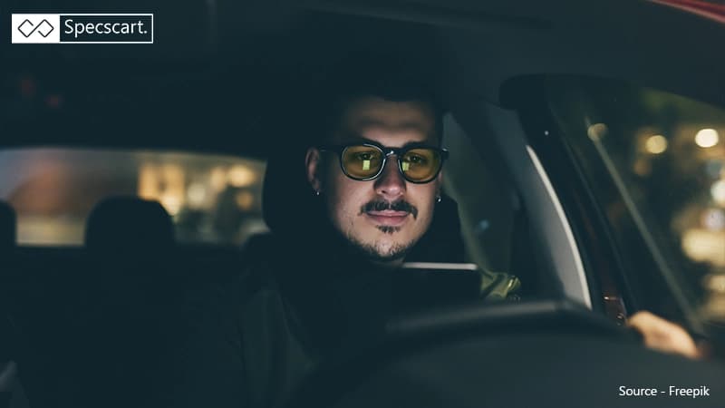 Yellow Tinted Lenses for Nighttime Driving A driver sits in a dark car wearing yellow-tinted glasses, demonstrating how these lenses are used to reduce glare and improve contrast at night.