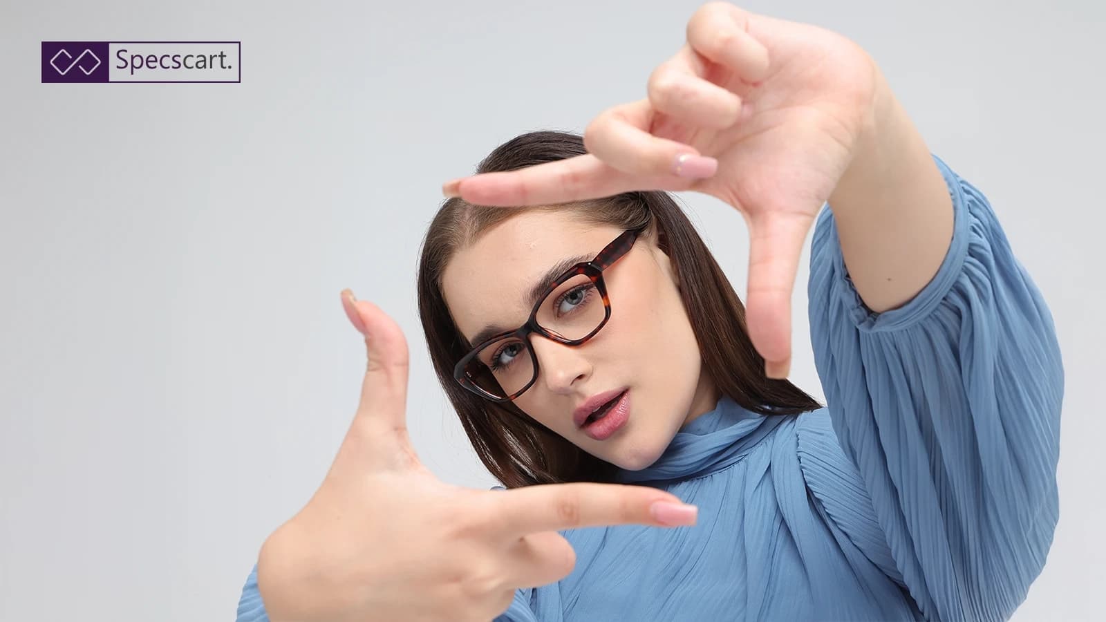 Why Do Your Eyes Need Time to Adjust to New Glasses? A woman wearing Specscart's dark tortoiseshell glasses while framing her face with her hands, highlighting the stylish aesthetic of the frames.