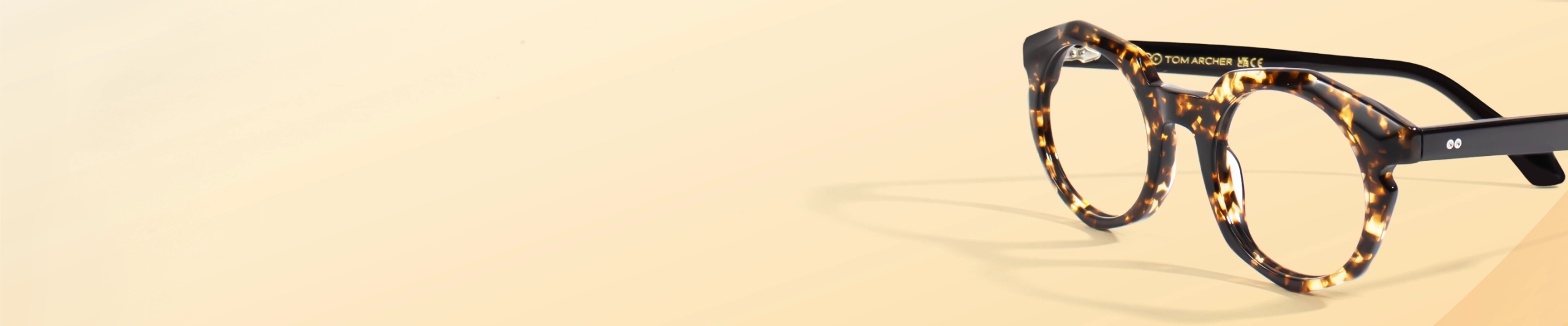 Leopard Print Glasses Leopard print round eyeglasses with yellow gradient tips displayed on a white cylindrical stand against a soft gradient background