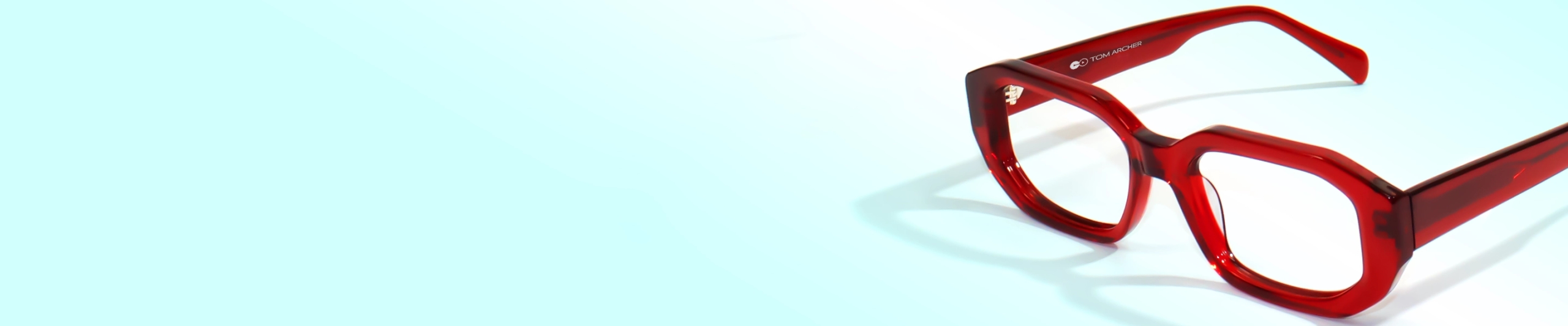 Red Glasses Close-up of stylish, bold, square glasses with bright, translucent red frames on a light blue background.