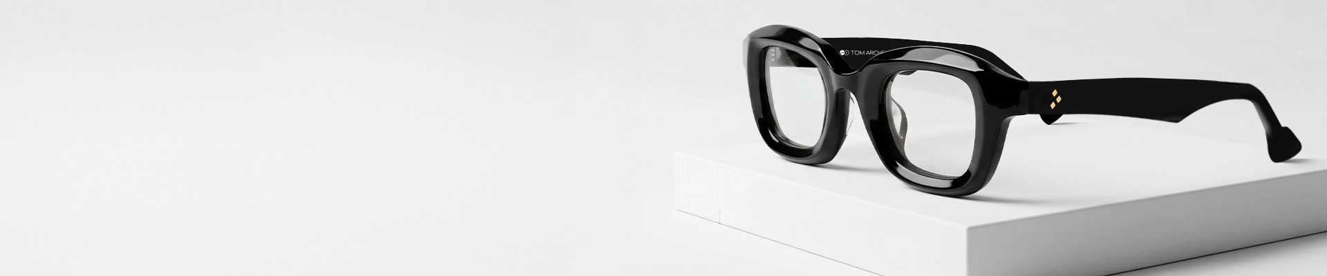 Black Glasses A close up image of black rectangular eyeglasses featuring a chunky black acetate frame placed on a textured stone surface. The image has content that says black glasses and a tagline. It also has a discount offer by Specscart and Trustpilot reviews.