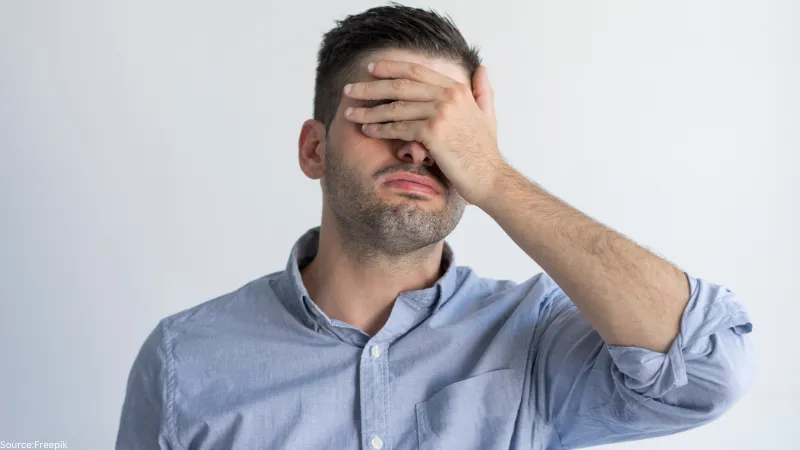 exhausted exhausted young man with stubble covering face with hand despair